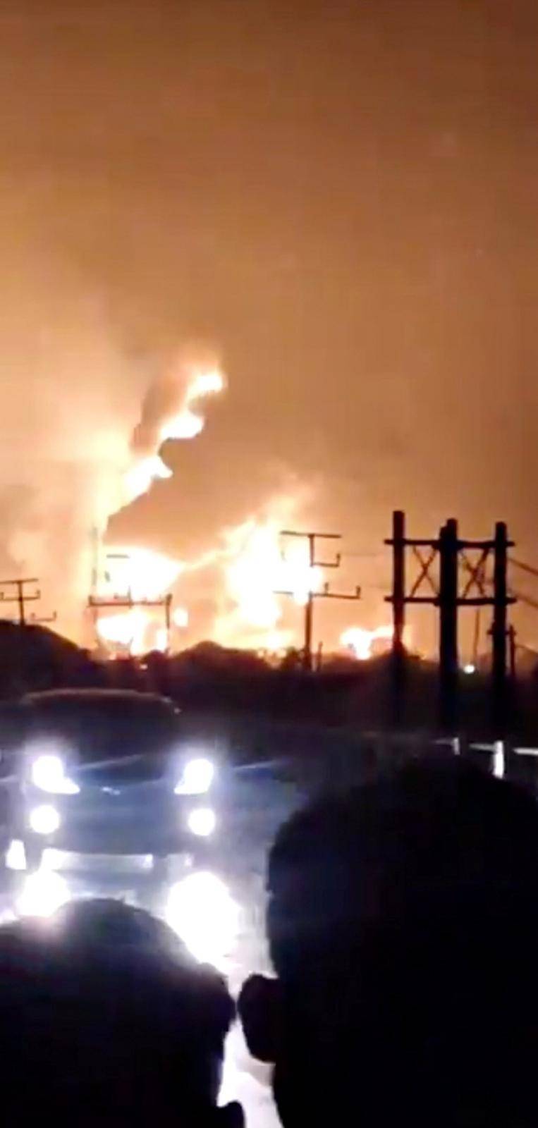 Motorists look at a refinery fire in Indramayu, Indonesia