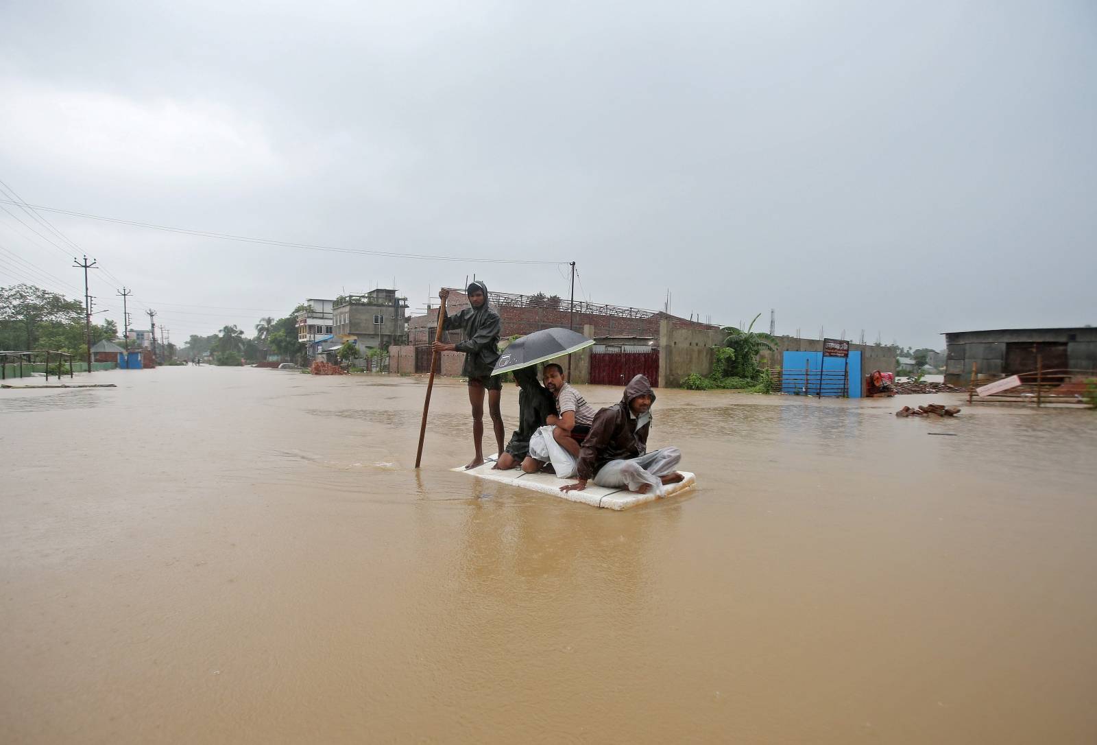 Villagers use a makeshift raft to cross a flooded area on the outskirts of Agartala