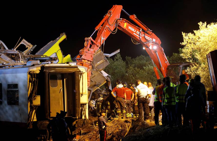 Rescuers work at the site where two passenger trains collided in the middle of an olive grove in the southern village of Corato