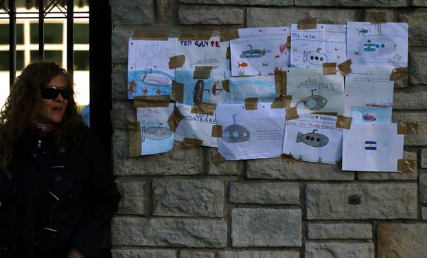 A woman stands next to drawings with messages in support of the 44 crew members of the missing at sea ARA San Juan submarine placed on a wall at the entrance of an Argentine naval base in Mar del Plata