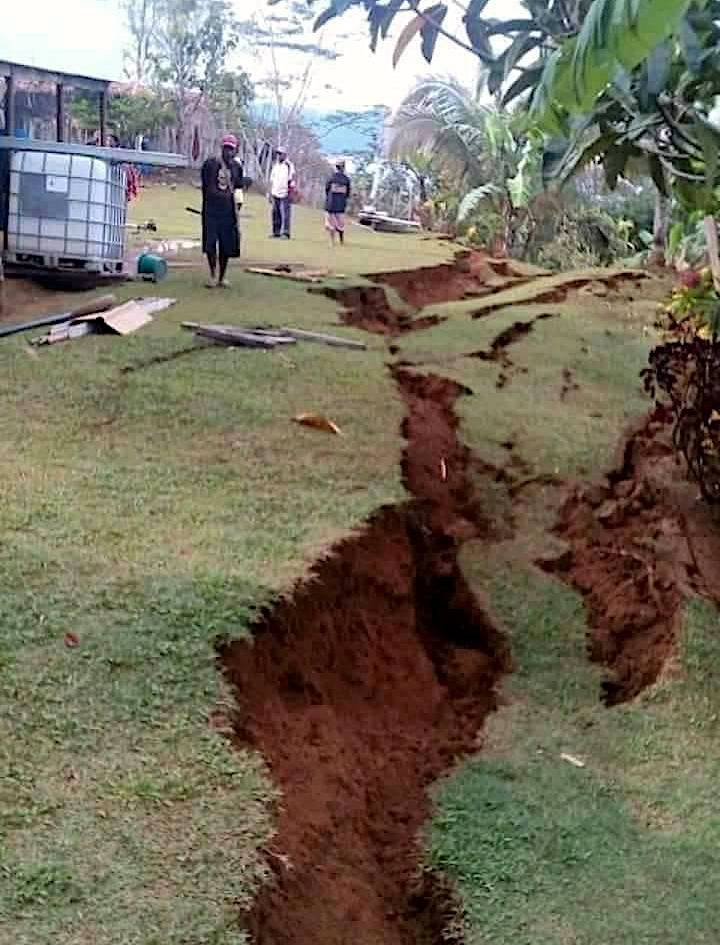 Locals stand next to a damaged house near a landslide in the town of Tari after an earthquake struck Papua New Guinea's Southern Highlands