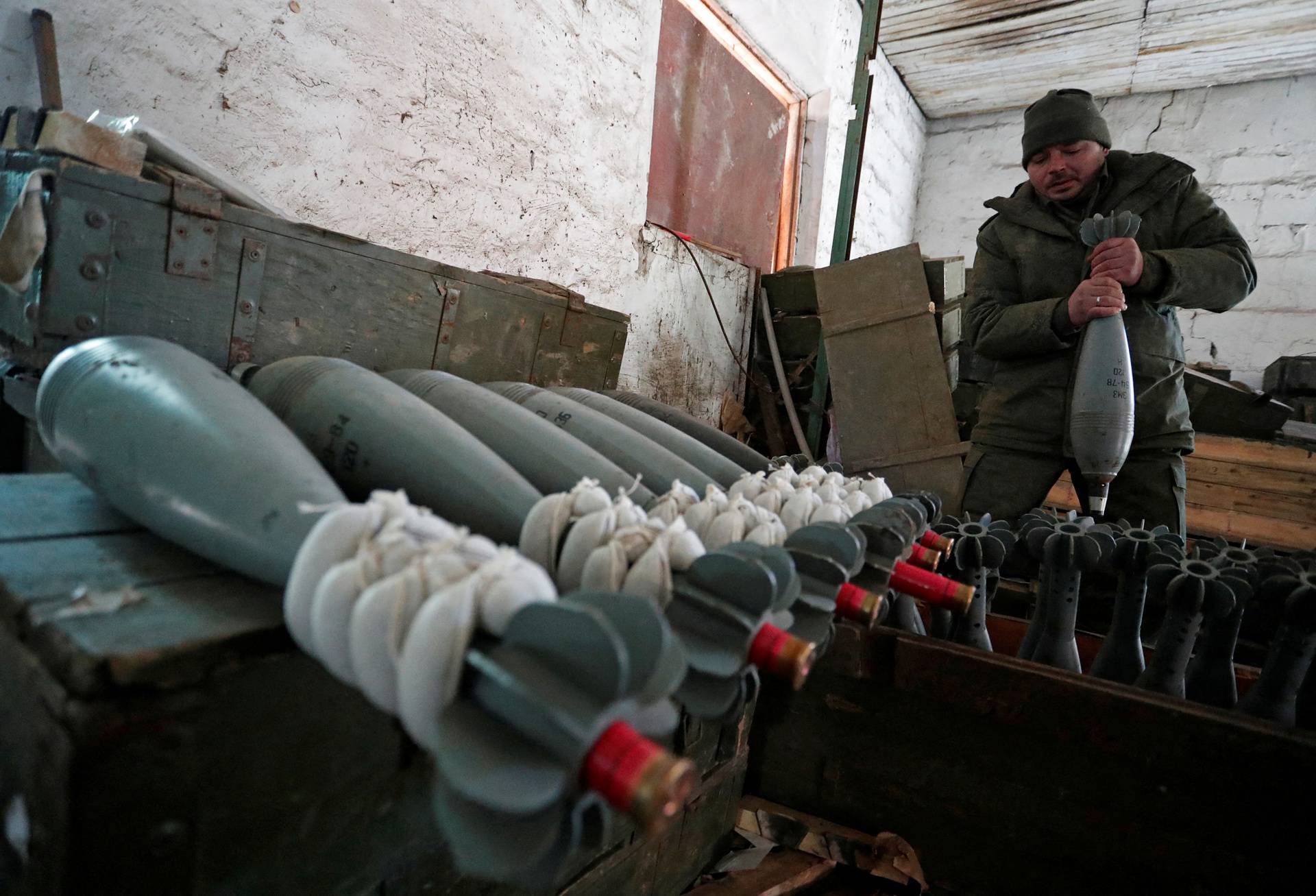 A service member of pro-Russian troops in uniform without insignia handles mortar round at the weapons depot near Marinka