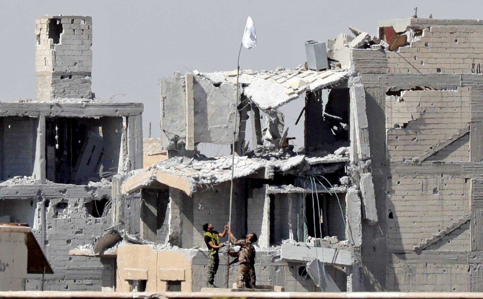 Fighters of Syrian Democratic Forces raise a white flag near the National Hospital complex where the Islamic State militants are holed up, at the frontline in Raqqa