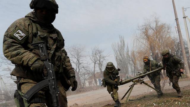 Service members of pro-Russian troops fire an anti-tank grenade launcher in Mariupol