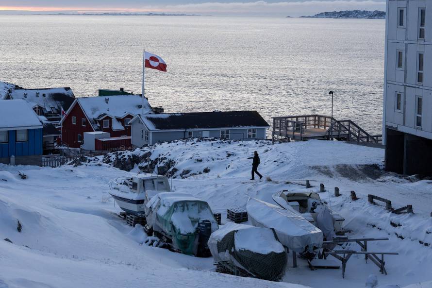 A Greenland flag flies as a man walks on the day of the meeting between top U.S. officials and the foreign ministers of Denmark and Greenland, in Nuuk
