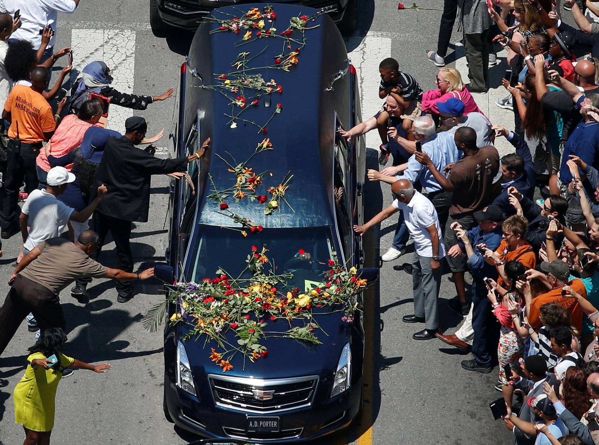 Well-wishers touch the hearse carrying the body of the late boxing champion Muhammad Ali during his funeral procession through Louisville, Kentucky