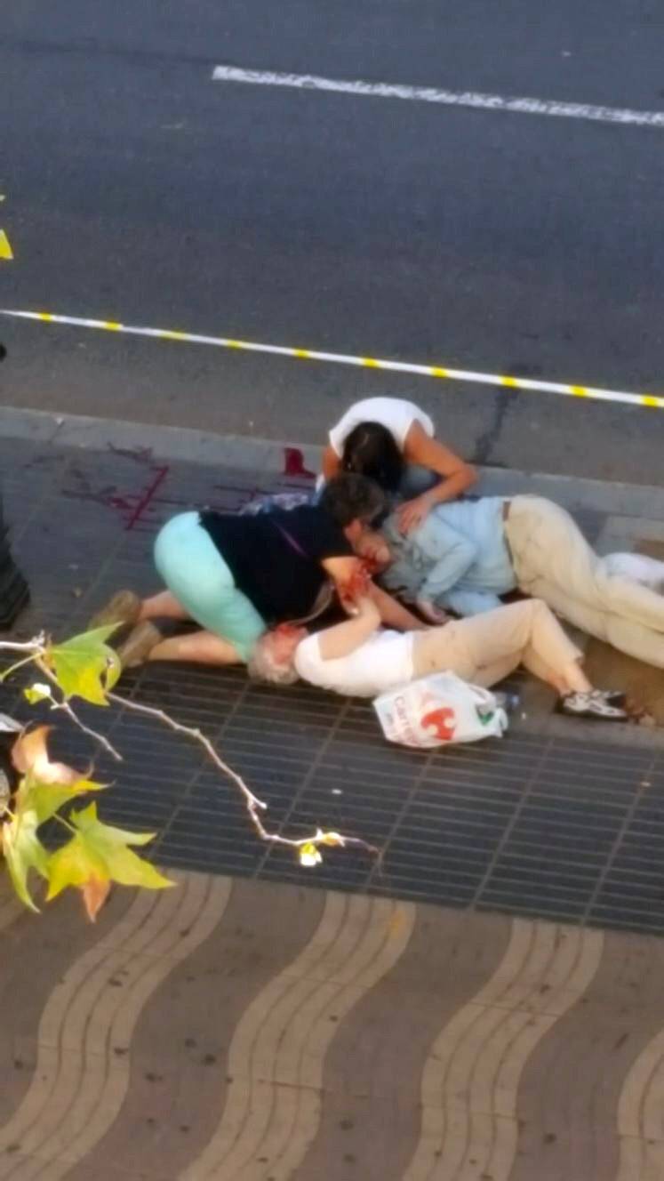 People attend to injured persons at the scene after a van crashed into pedestrians near the Las Ramblas avenue in central Barcelona