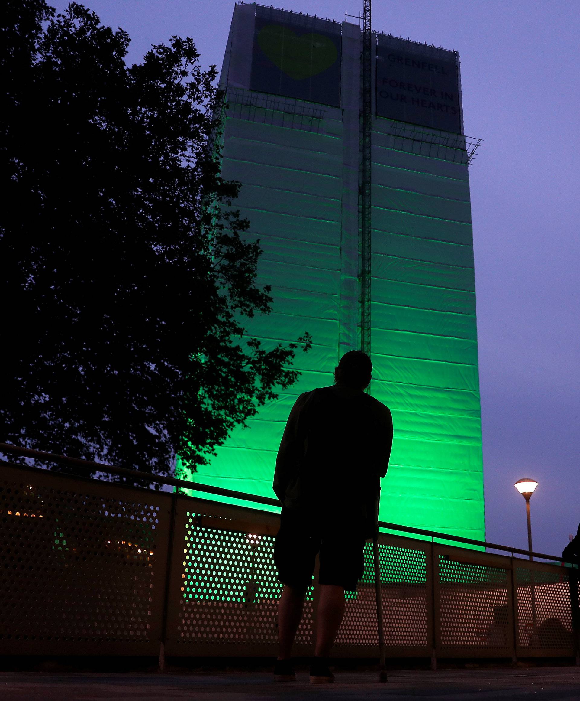 Grenfell Tower is seen covered and illuminated with green light one year after the tower fire in London