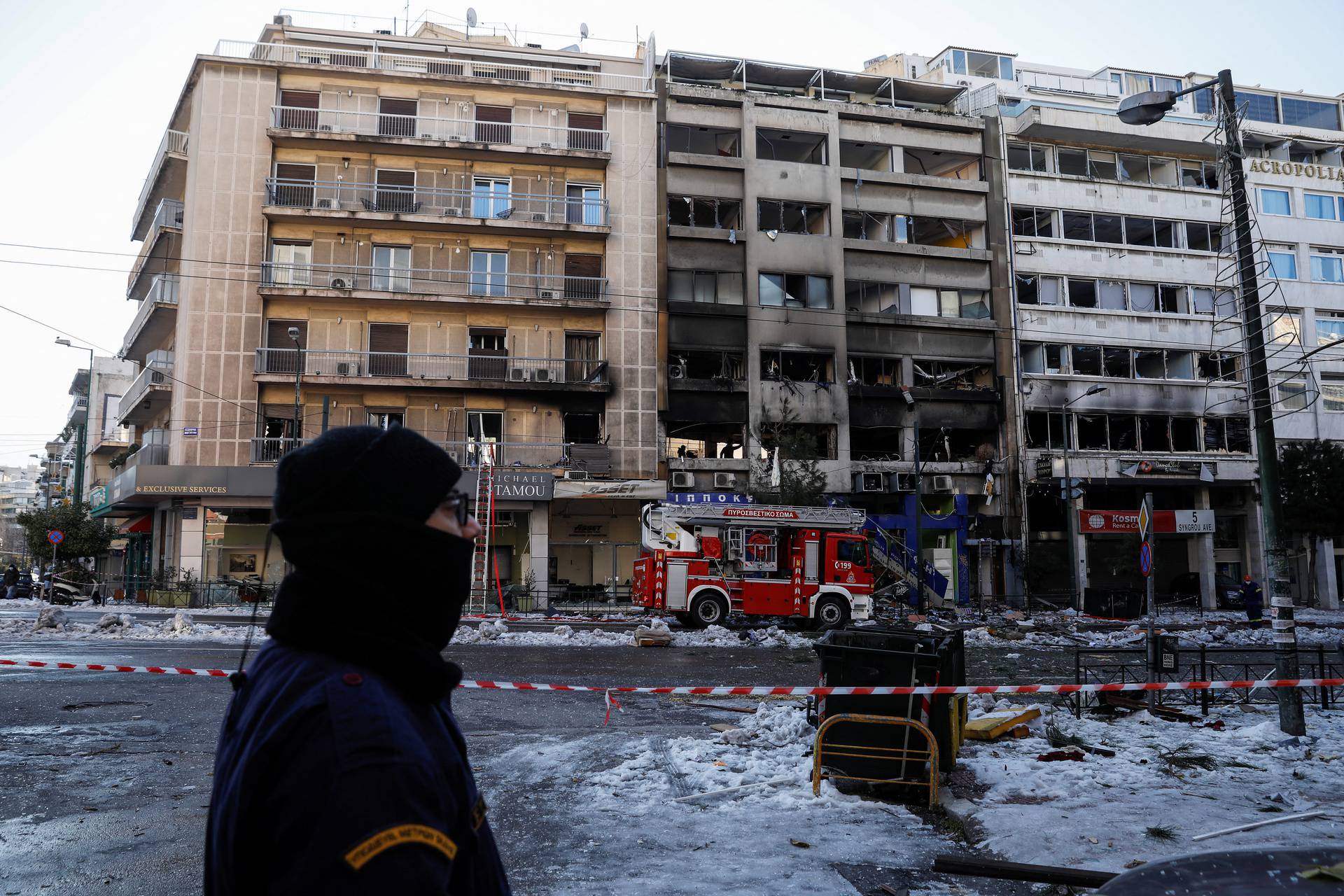 A police officer stands guard opposite damaged buildings after a blast in Athens