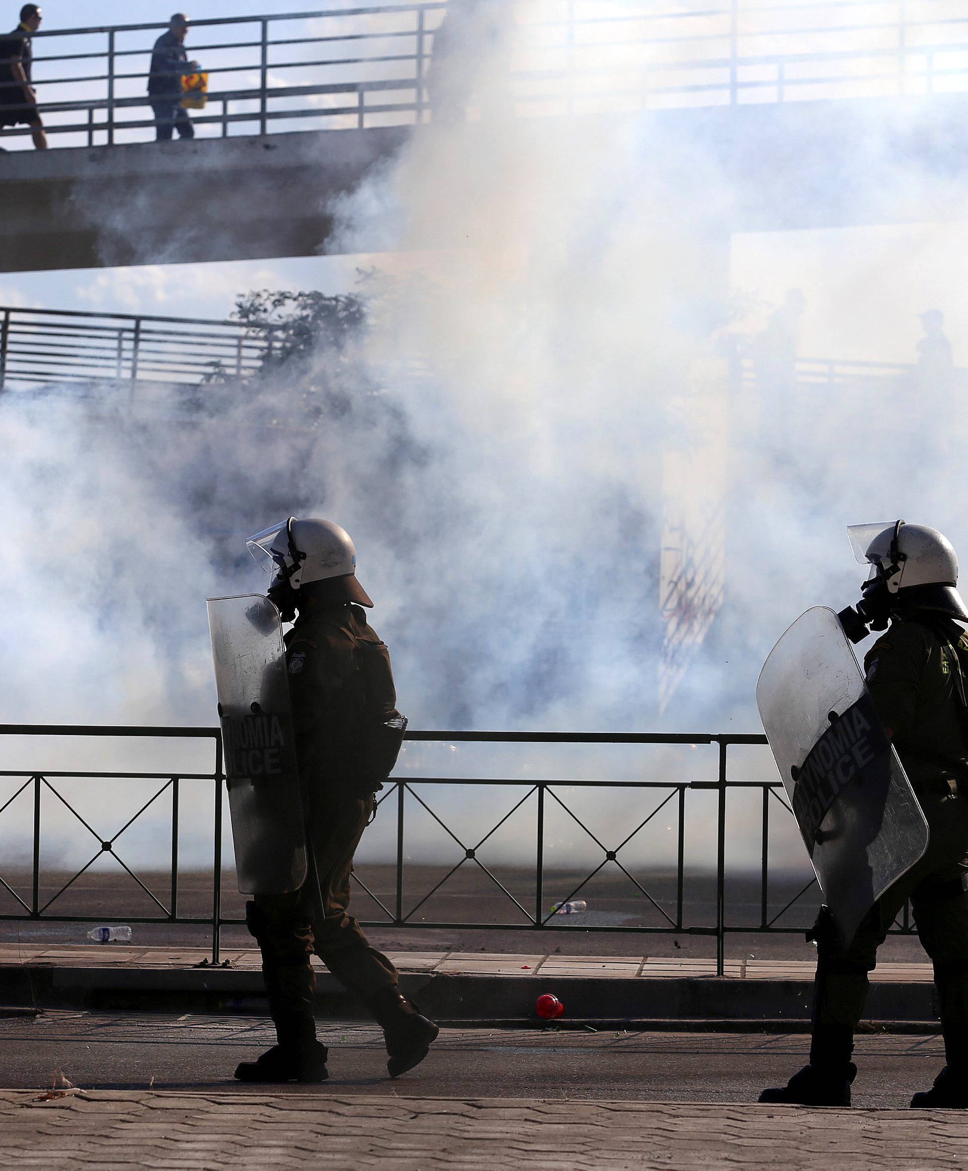 Riot police walk amid tear gas during clashes with fans before the Greek Cup Final soccer game between PAOK Salonika and AEK Athens at Panthessaliko stadium in Volos