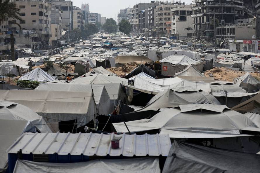 Palestinians, displaced by the Israeli military offensive, shelter in a tent camp, in Gaza City