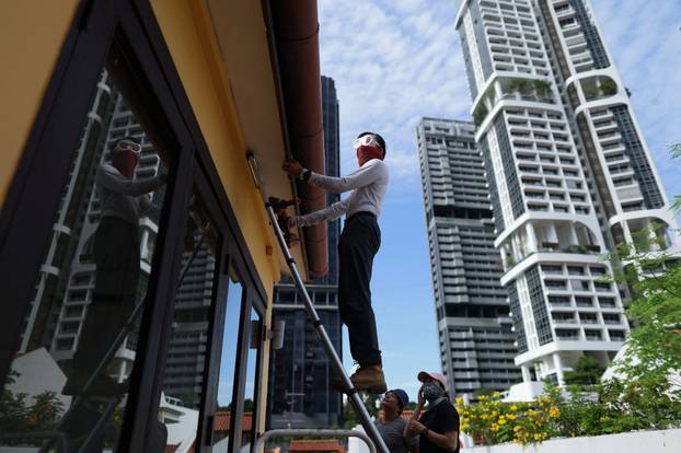 Bee rescuer Clarence Chua, inspects the roof of an apartment for bee nests in Singapore