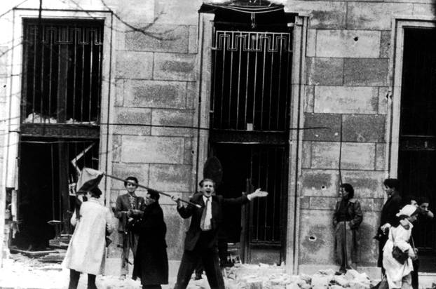 November 1956, Budapest, rebels assault the building behind the tank. The attack is a success, and a standard bearer announces that the building is captured and the police is ready to come out. November 10, 1956 Hungary - Hungarian uprising of 1956  Natio