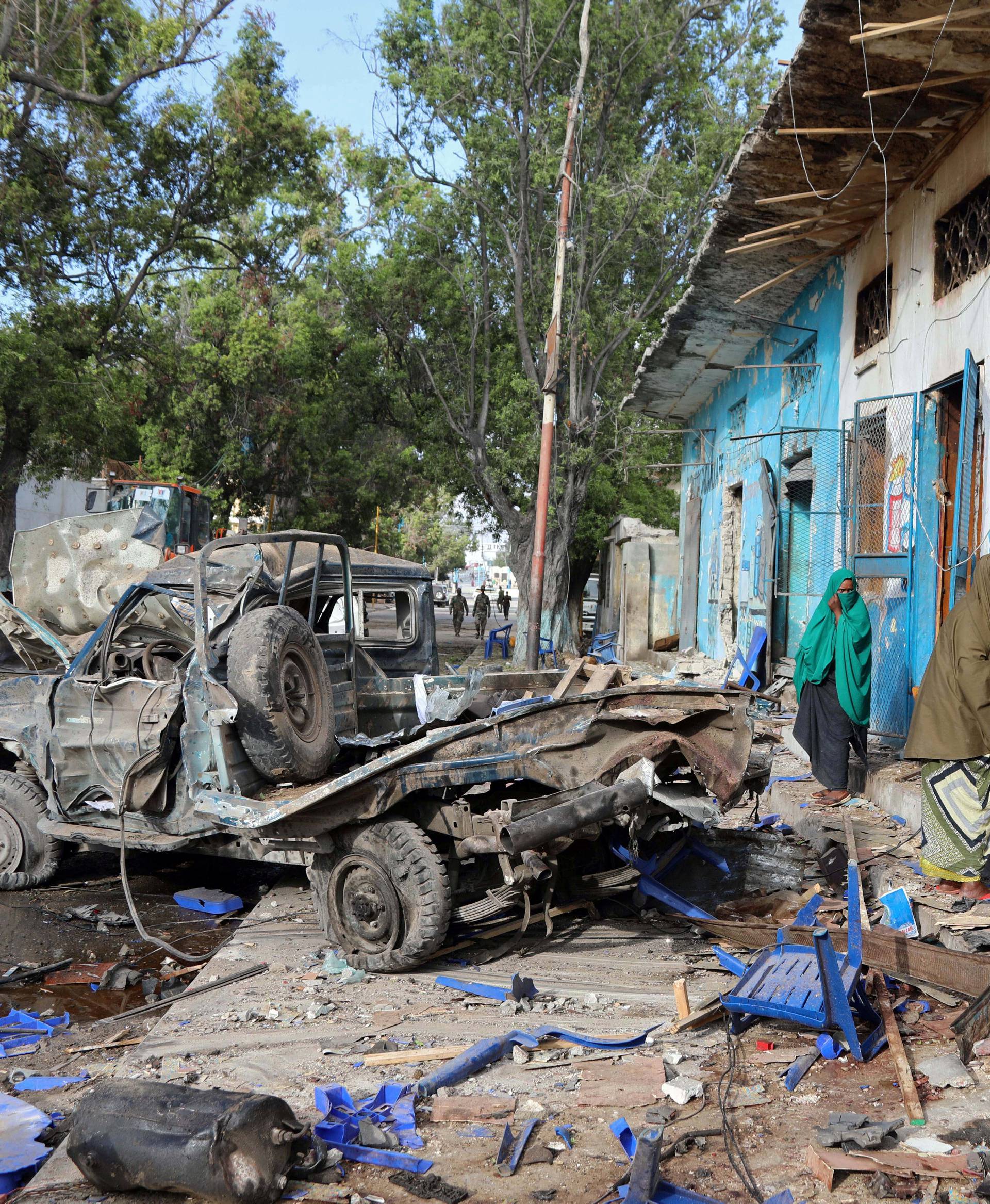 Residents gather at the scene of a suicide car bomb explosion, at the gate of Naso Hablod Two Hotel in Hamarweyne district of Mogadishu