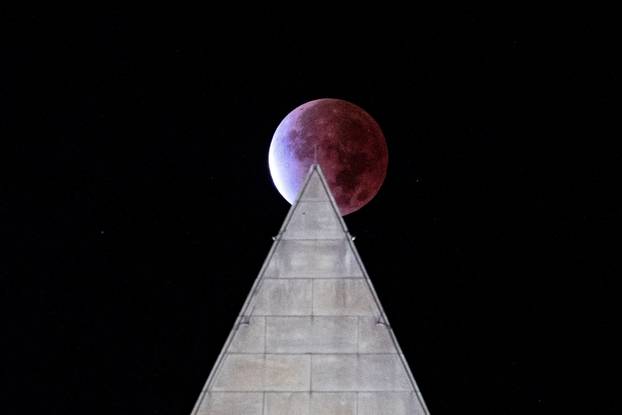 The Beaver 'blood' Moon partial lunar eclipse is seen above the Washington Monument in Washington