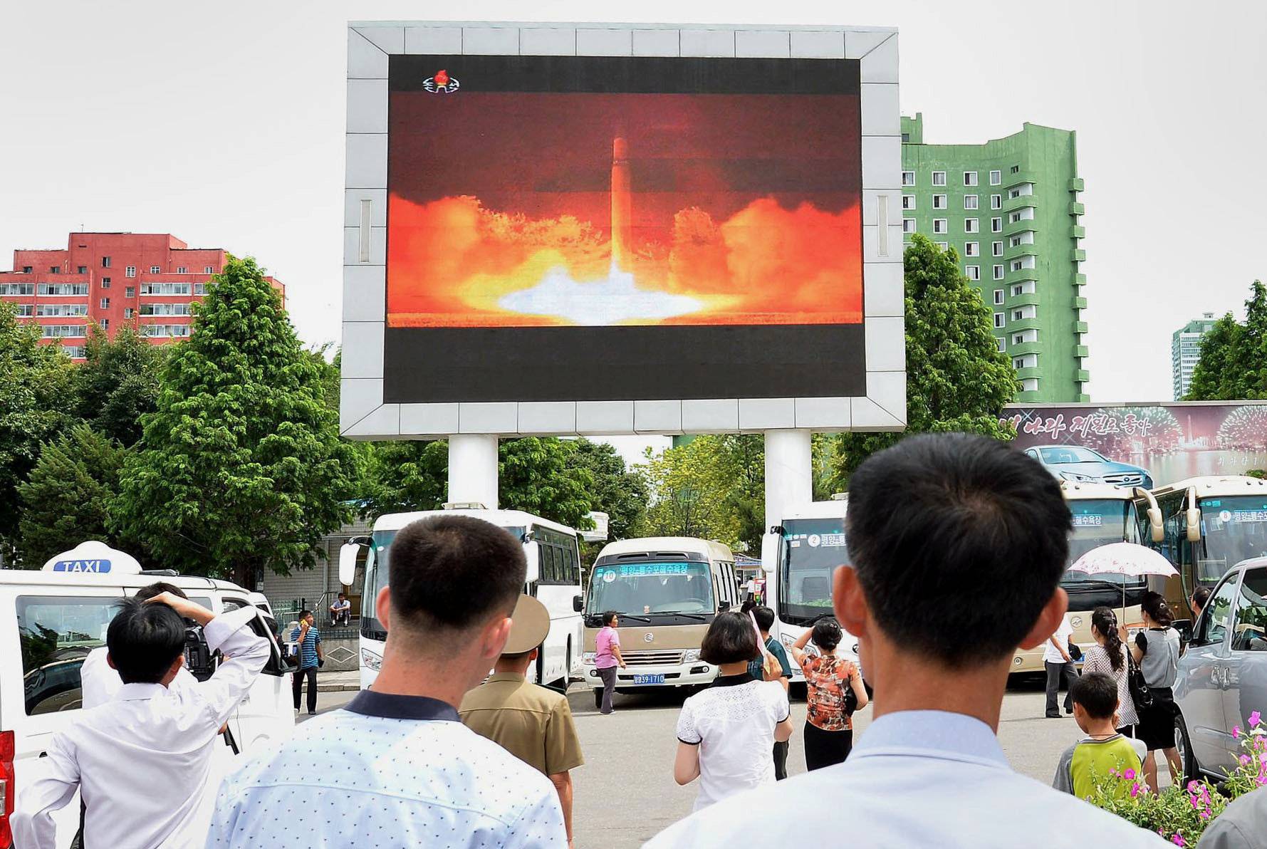 People watch news report showing North Korea's Hwasong-14 missile launch on electronic screen at Pyongyang station