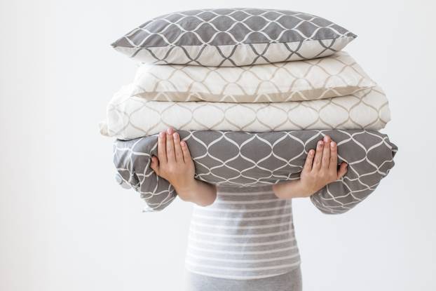 Hands,Of,Woman,Holding,Modern,Beige,And,Grey,Bed,Linen