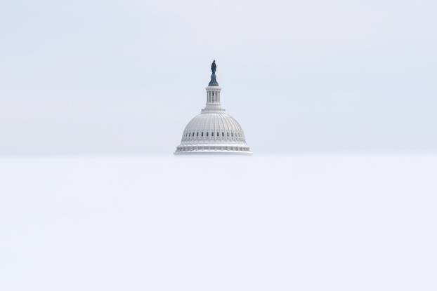 The U.S. Capitol dome rises above a snow-covered hill after a winter storm in Washington