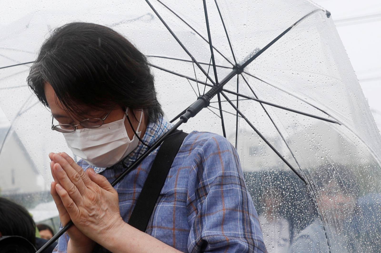 A woman prays for the victims of the arson attack in front of the torched Kyoto Animation building n Kyoto