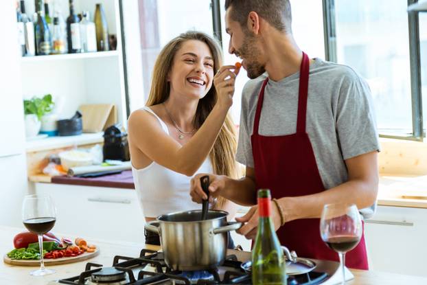 Happy young couple cooking together in the kitchen at home.