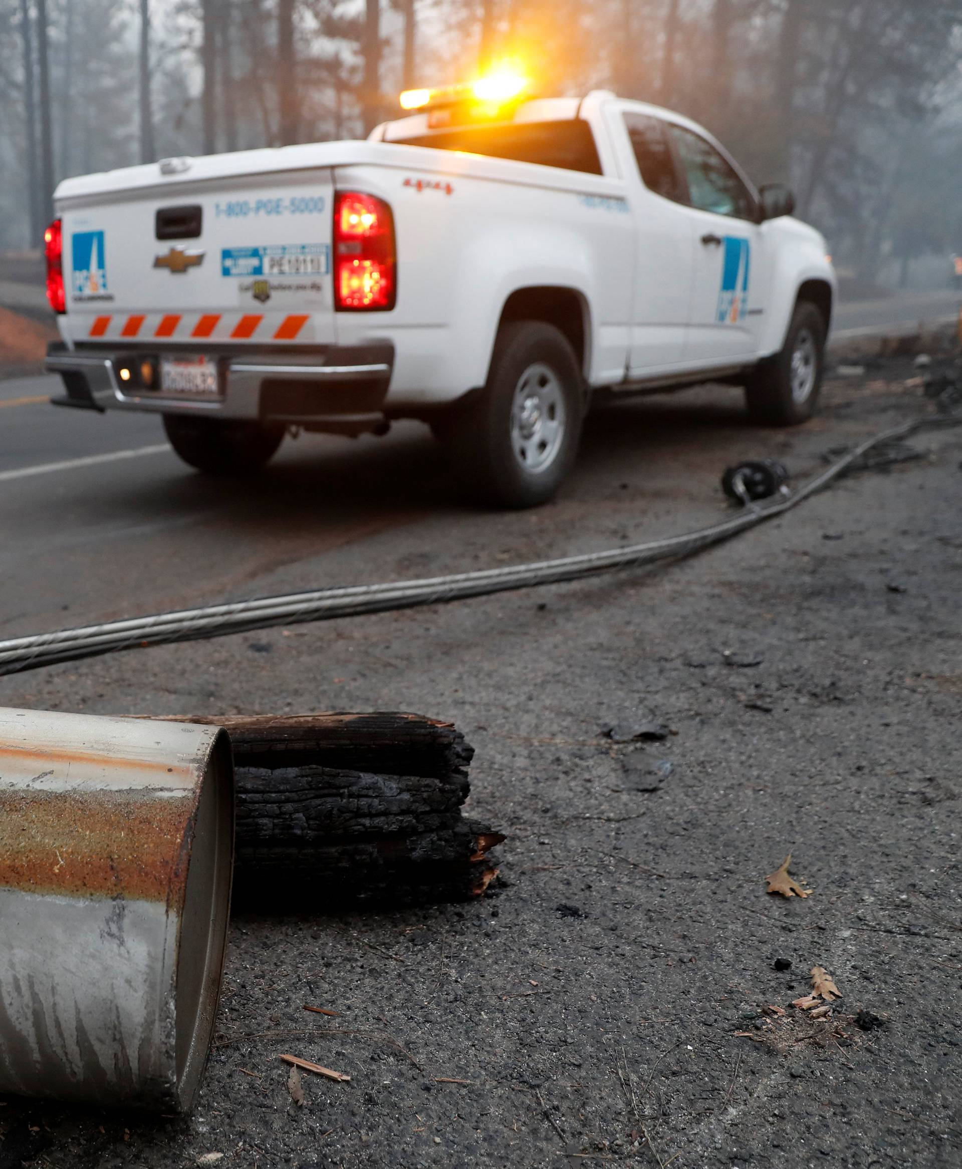 An electricity pole damaged by the Camp Fire lies near a Pacific Gas & Electric truck in Paradise