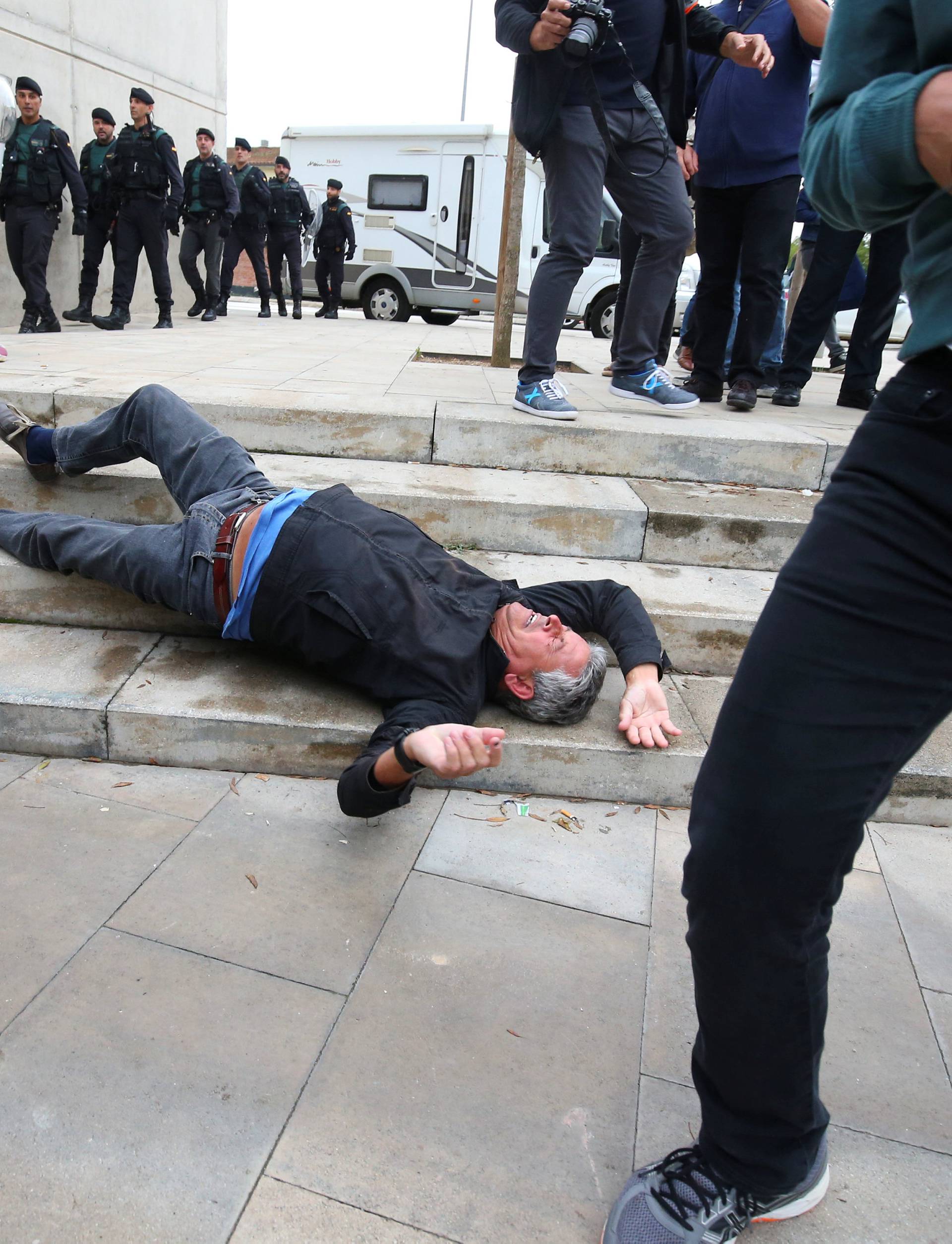 A man falls to the ground during scuffles with Spanish Civil Guard officers outside a polling station for the banned independence referendum in Sant Julia de Ramis