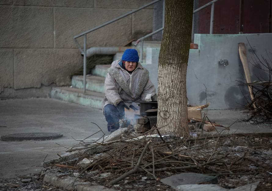 A local resident prepares a food on a wooden stove near her building in Bakhmut