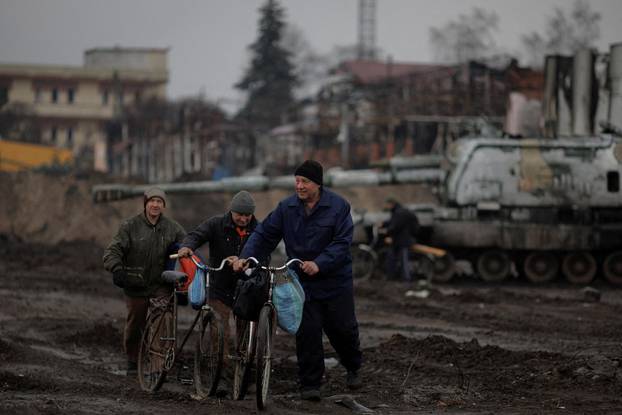 Locals walk in the demolished town center of Trostyanets after Ukrainian forces expelled Russian troops from the town which Russia occupied at the beginning of its war with Ukraine