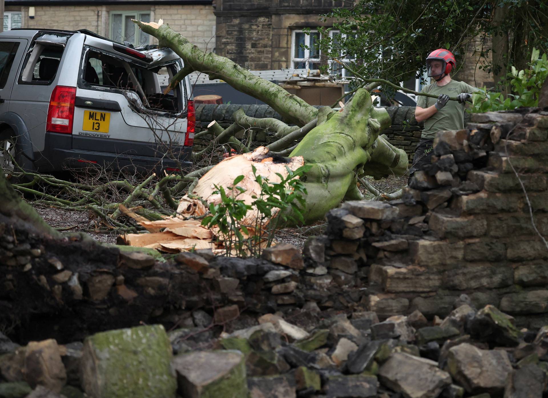 Tree surgeon works to remove a tree that fell onto a car after Storm Gerrit hit the country in Stalybridge