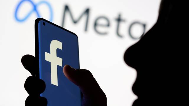 FILE PHOTO: Woman holds smartphone with Facebook logo in front of Facebook's new rebrand logo Meta in this illustration picture