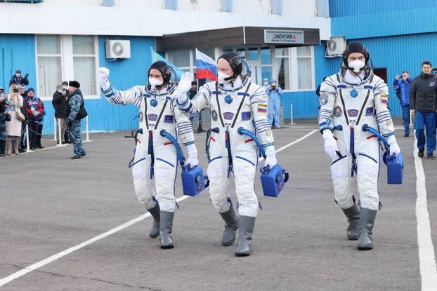 Russian cosmonauts walk before departing for boarding the Soyuz MS-21 spacecraft at the Baikonur Cosmodrome