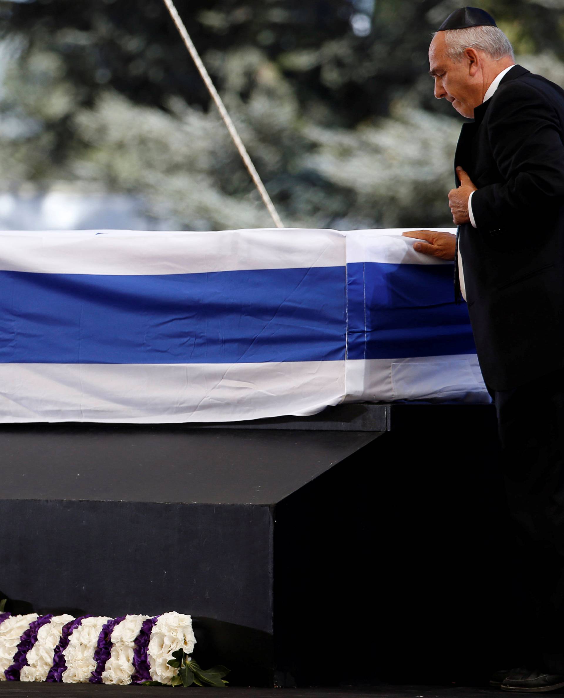 Chemi Peres, son of former Israeli President Shimon Peres, touches his father's flag-draped coffin after eulogising him during his funeral ceremony at Mount Herzl cemetery in Jerusalem