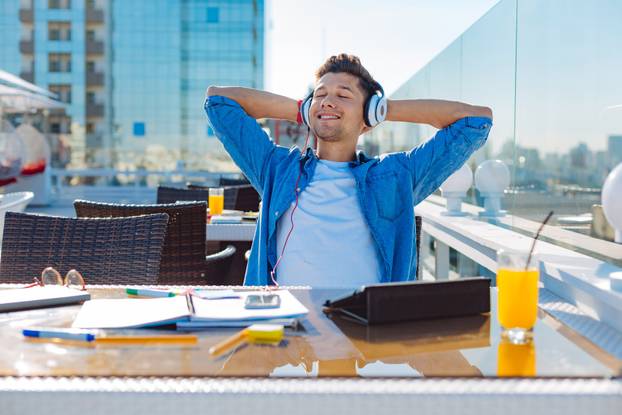 Relaxed college student enjoying music playing in headphones