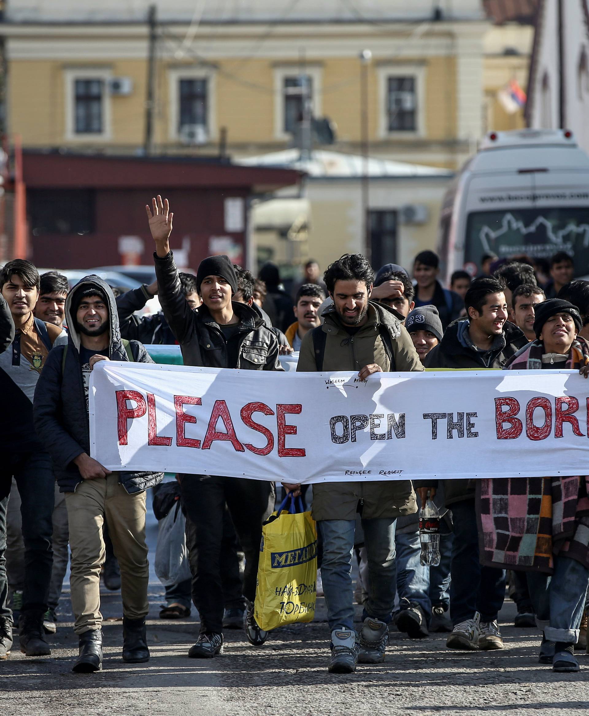 Refugees and migrants hold a banner and shout slogans as they walk heading in the direction of the Croatian border, in Belgrade