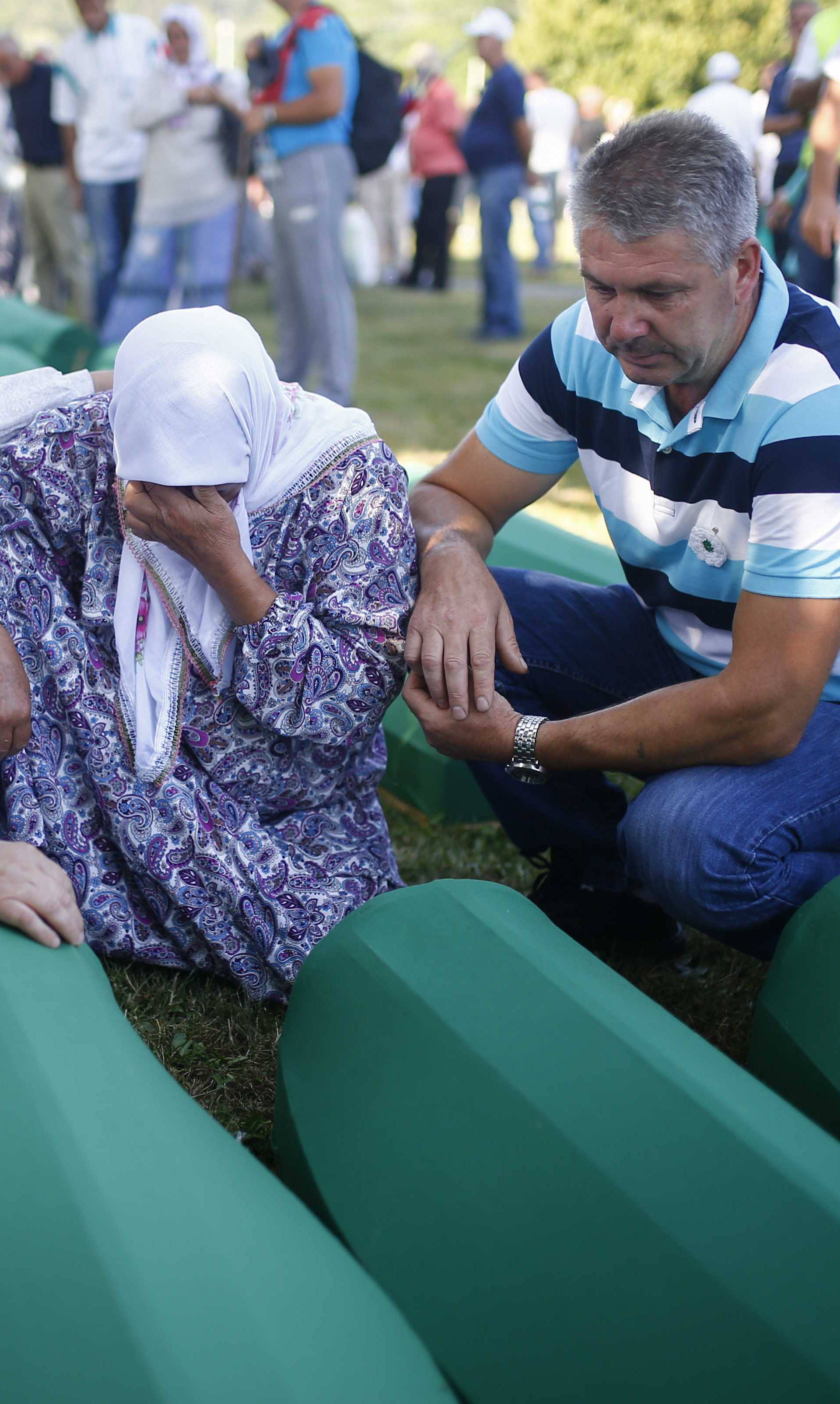 People mourn near coffins of their relatives, who are newly identified victims of the 1995 Srebrenica massacre, which are lined up for a joint burial in Potocari near Srebrenica