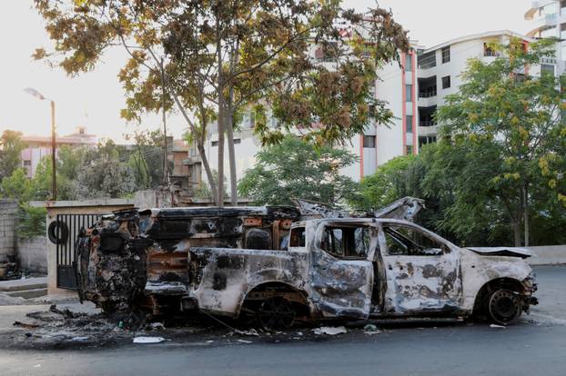 Damaged vehicles remain along a street in Sweida