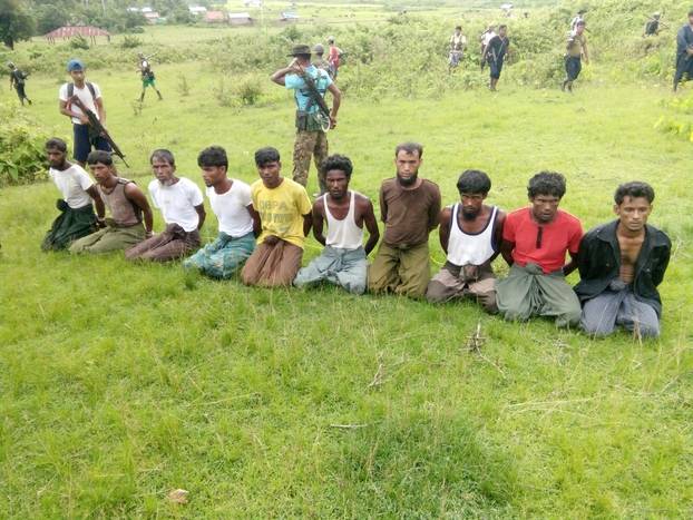 FILE PHOTO: Ten Rohingya Muslim men with their hands bound kneel as members of the Myanmar security forces stand guard in Inn Din village