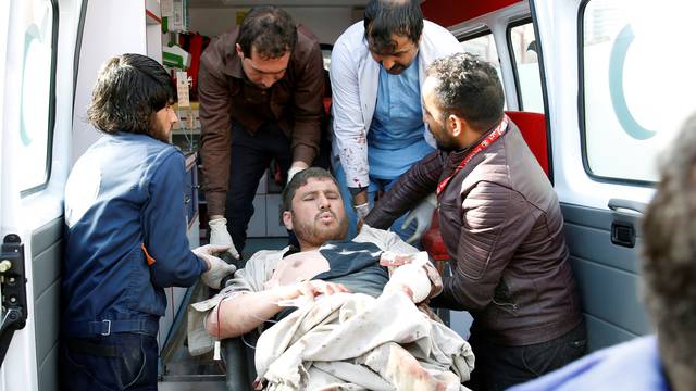 People carry an injured man to a hospital after a blast in Kabul