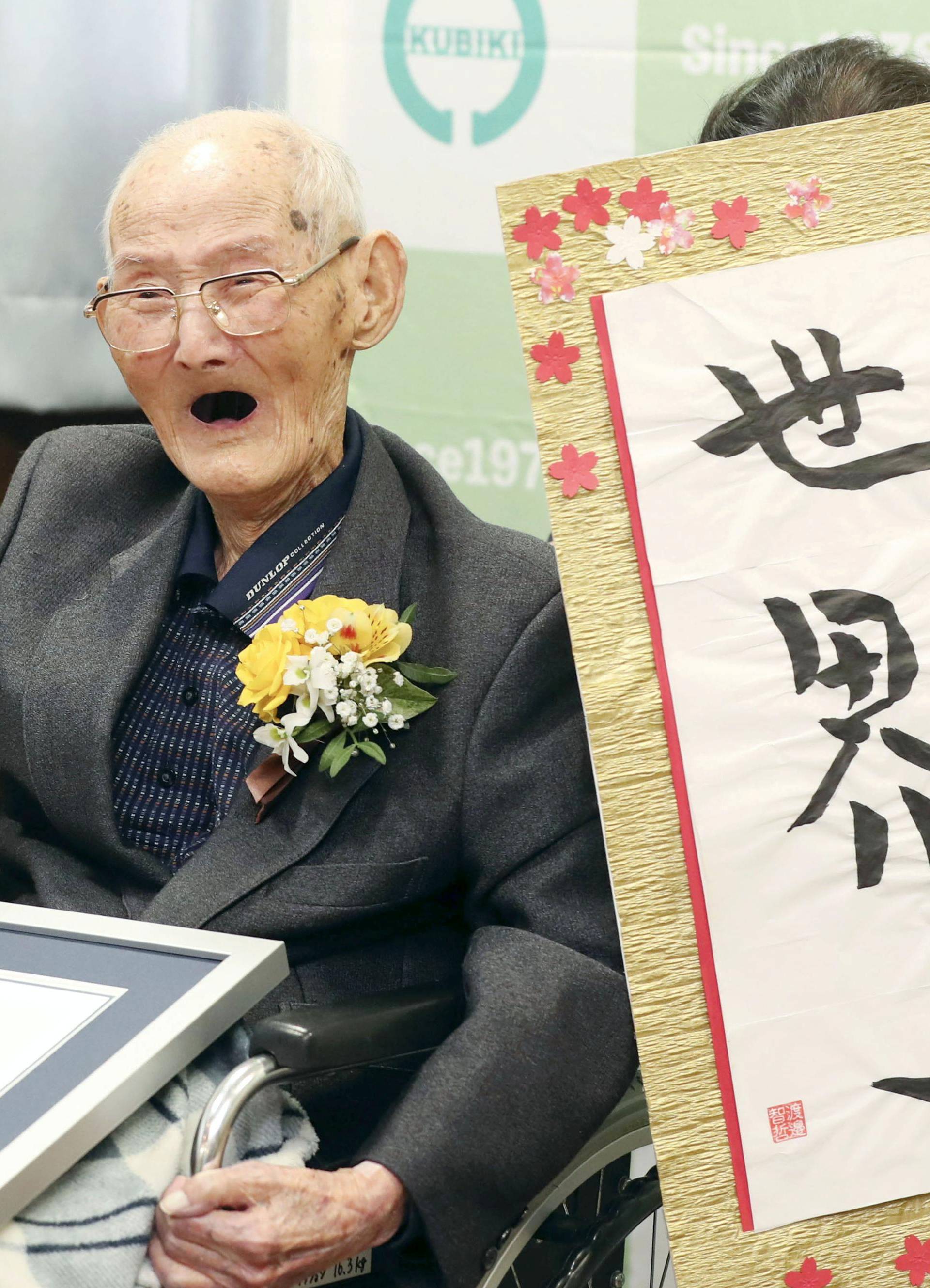 112-year-old Chitetsu Watanabe poses next to the calligraphy reading 'World Number One' after being awarded as the world's oldest living male by Guinness World Records, in Joetsu, Japan