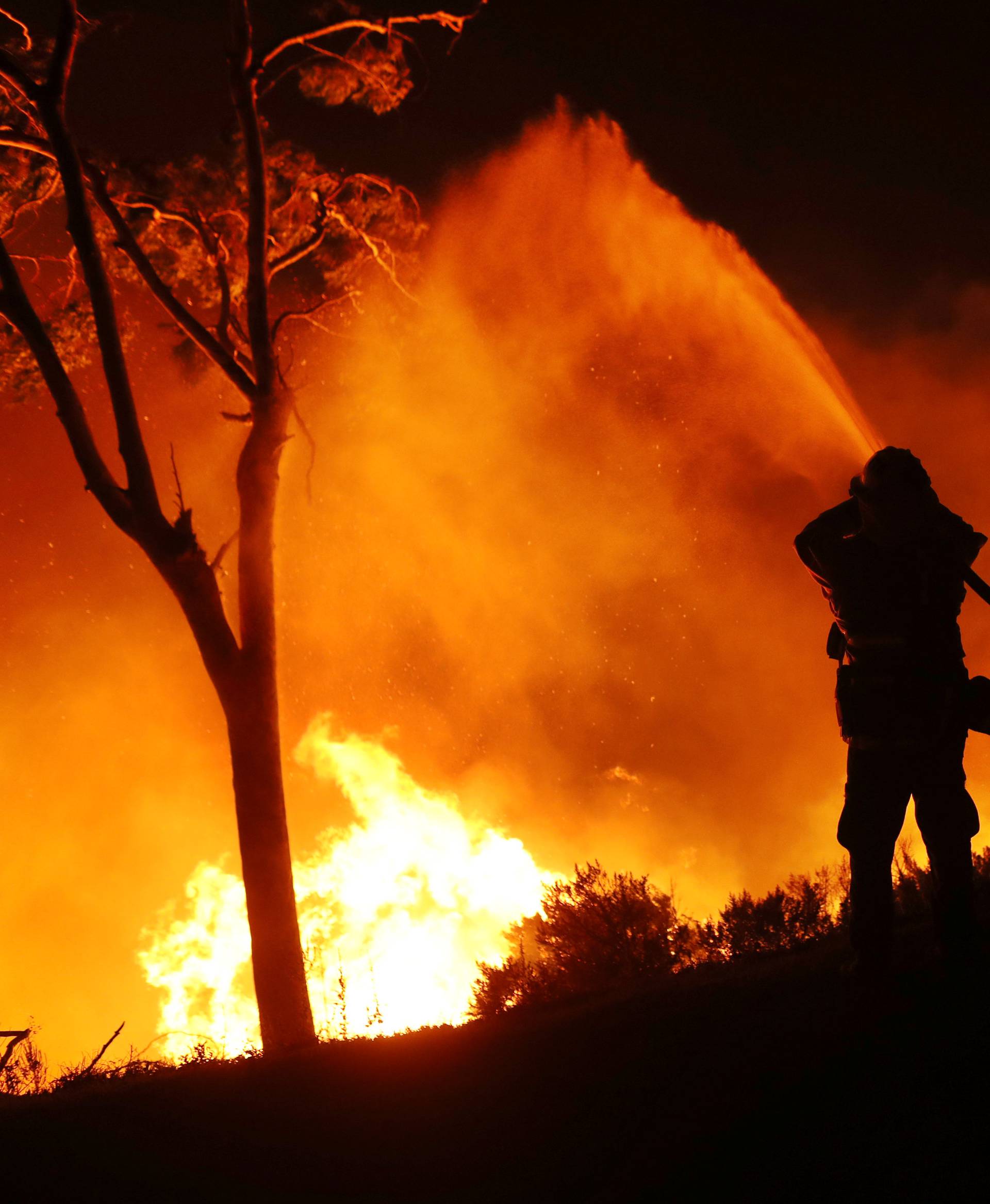 A firefighter working on extinguishing the Lilac Fire a fast moving wildfire is seen in Bonsall