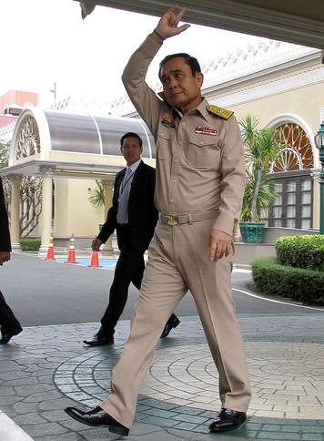 Thailand's Prime Minster Prayuth Chan-ocha waves to reporters next to a cardboard cut-out of himself at the government house in Bangkok