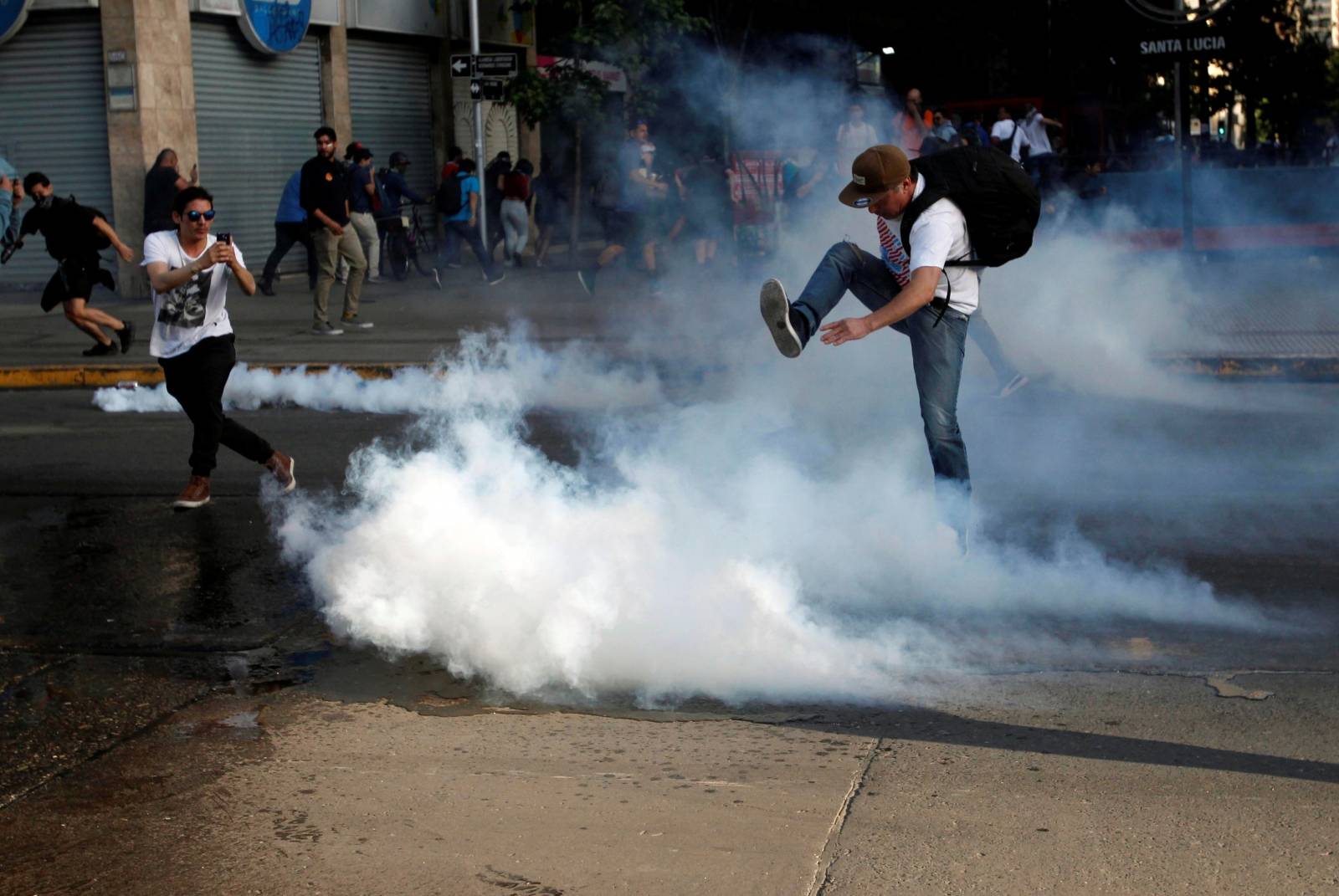 A demonstrator kicks a tear gas canister during a protest against the increase in the subway ticket prices in Santiago