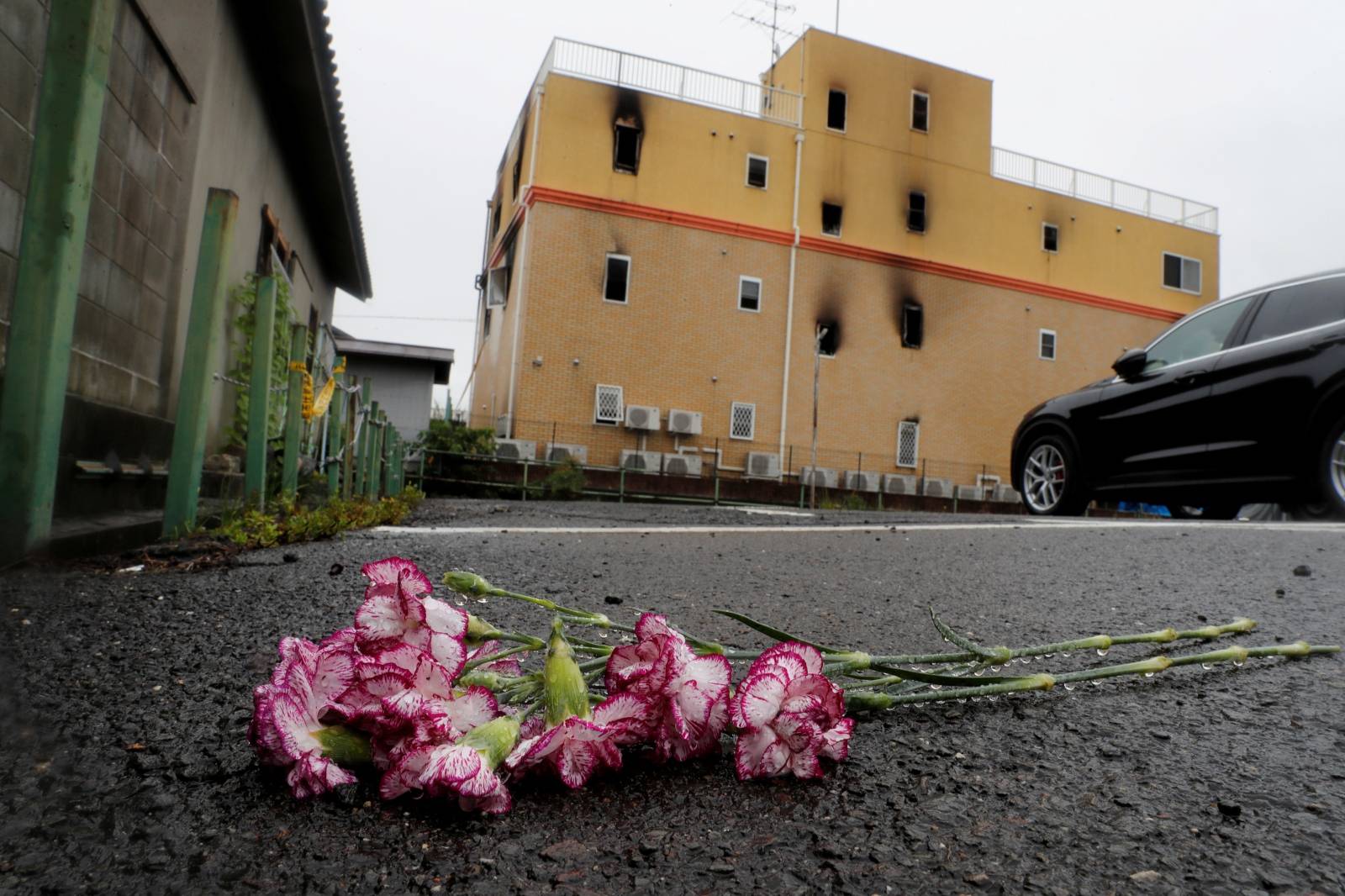 Flowers are placed in front of the torched Kyoto Animation building to mourn the victims of the arson attack in Kyoto