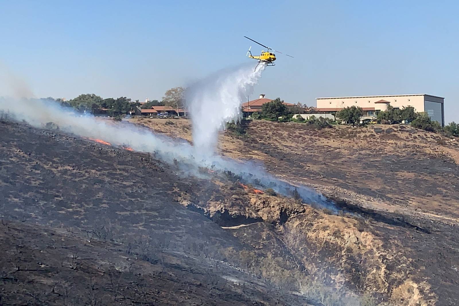 Helicopter drops water on a fire burning on a hillside near the Reagan Presidential library in Simi Valley