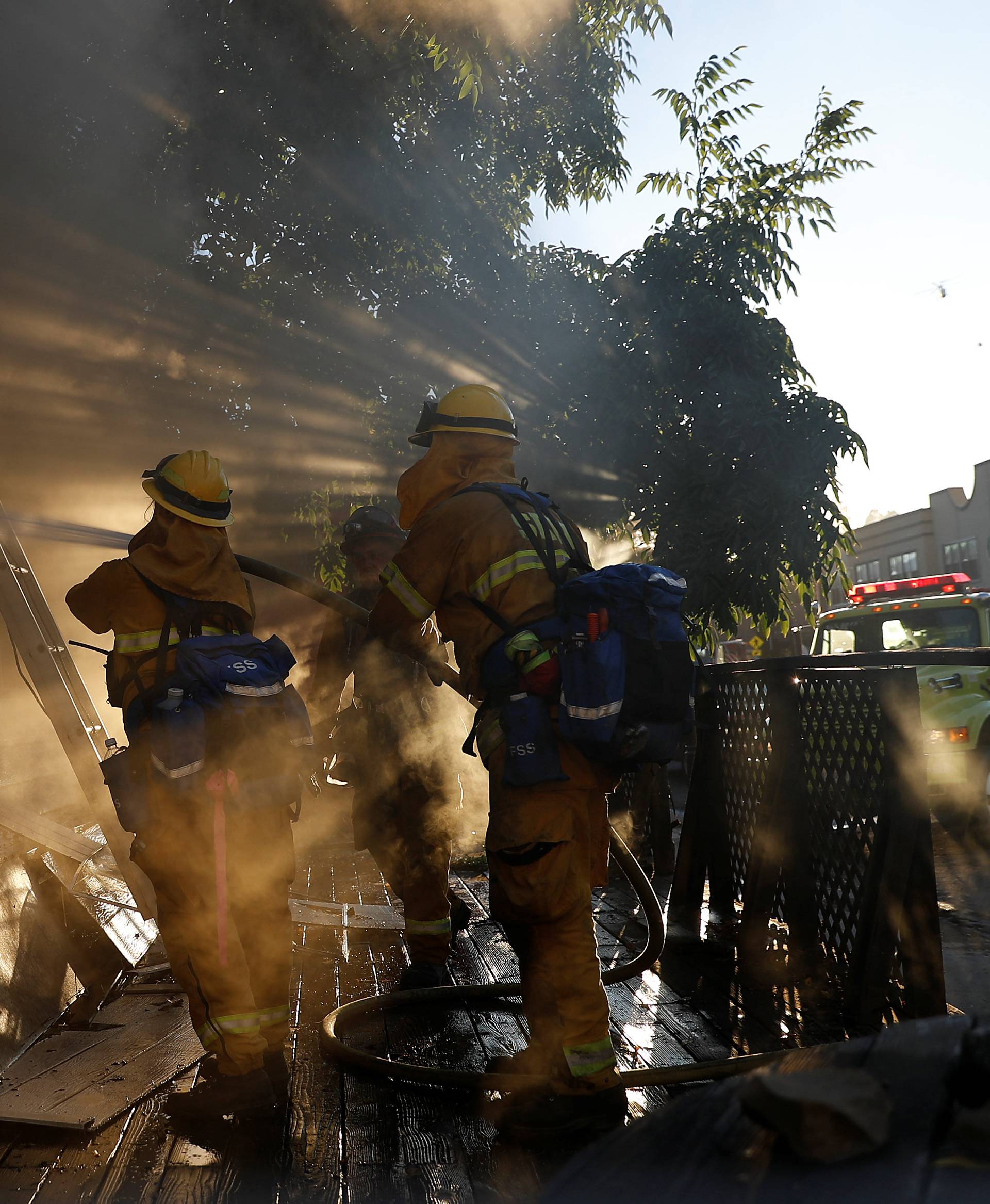 Firefighters spray water into a damaged building while battling the Clayton Fire near Lower Lake in California