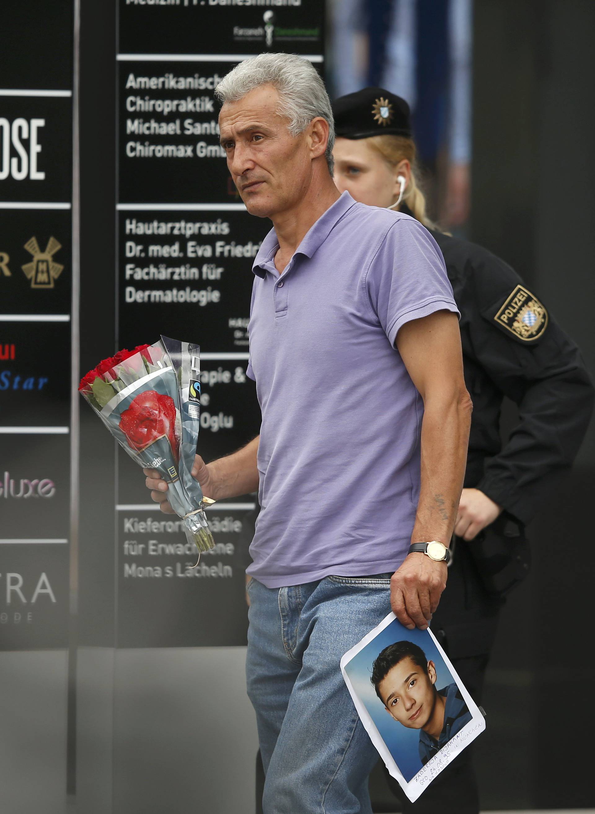 Man holding photo he claims is his slain son approaches police cordon near Olympia shopping mall in Munich