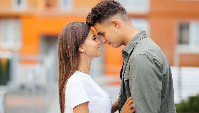 Happy teen couple embracing at street.