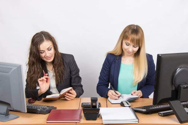  Two business women looking at diaries and make a plan of the day