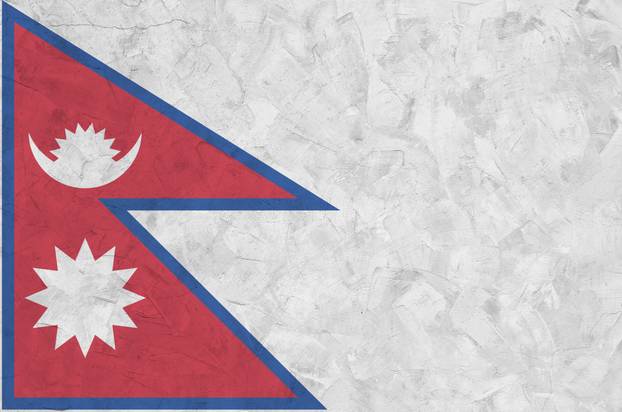 Nepal flag depicted in bright paint colors on old relief plastering wall. Textured banner on rough background
