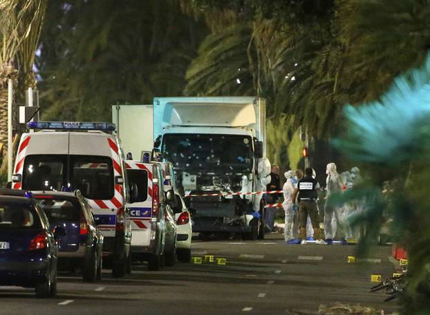 French police forces and forensic officers stand next to a truck that ran into a crowd celebrating the Bastille Day national holiday on the Promenade des Anglais killing at least 60 people in Nice